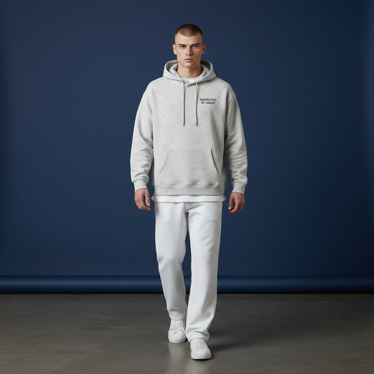 Model wearing an Omina grey oversized fleeced hoodie with Protected By Grace text against a dark blue background.