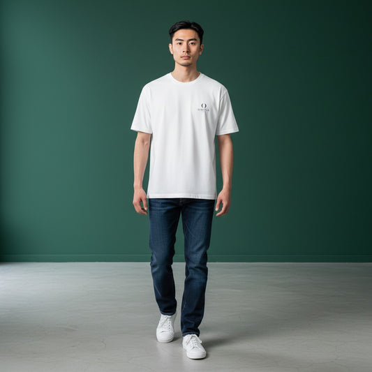 Model wearing an Omina white ring-spun cotton minimalist t-shirt with a small chest logo, paired with blue jeans.
