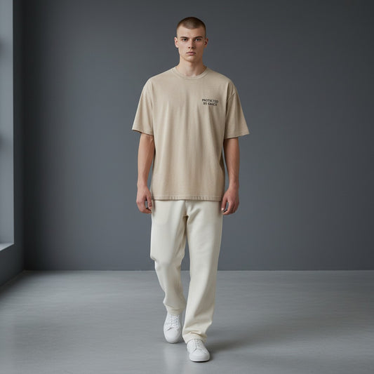 OMINA Studio beige heathered cotton t-shirt with "PROTECTED BY GRACE" text on the left chest.
