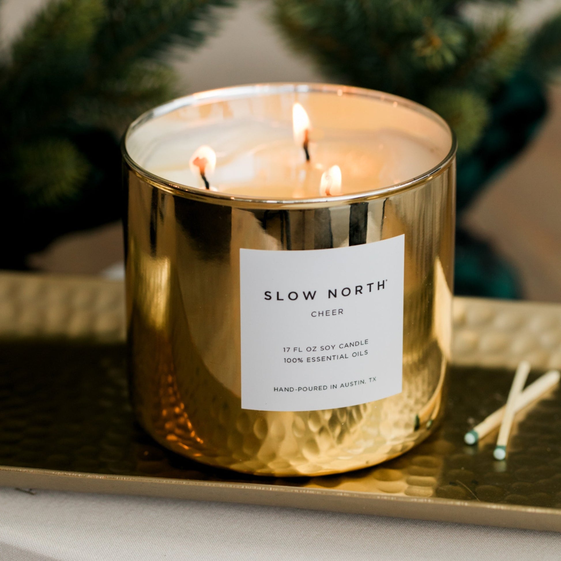 Slow North Cheer Signature 3-Wick Candle with seasonal holiday fragrance in a clear glass jar with three wicks.