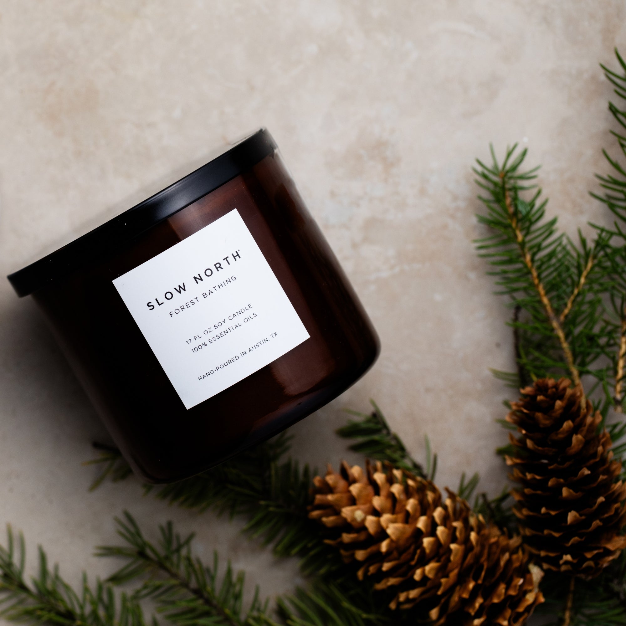 Slow North Forest Bathing Signature 3-Wick Candle with lush green foliage and wooden accents in a clear glass jar.