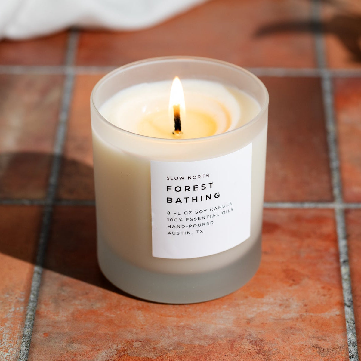 Frosted Forest Bathing signature candle by Slow North with fir, pine, and patchouli scents in a frosted glass container.