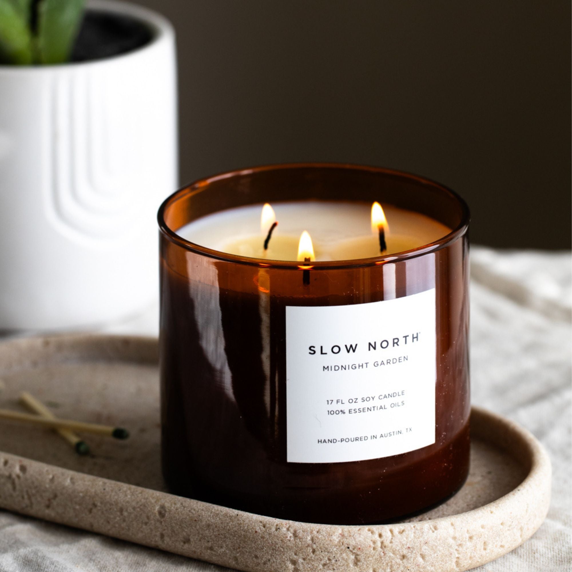 Slow North Midnight Garden Signature 3-Wick Candle with lavender, rosemary, and geranium floral scents, in a glass jar.