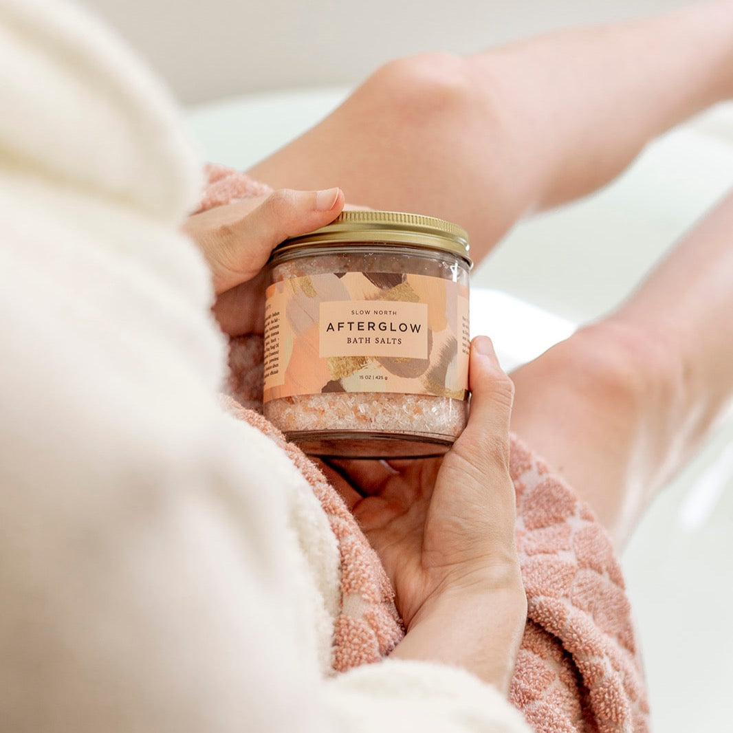 Slow North Afterglow Bath Salts in 15 oz jar, showing a clear glass container filled with pink and white bath salts for relaxing body care.
