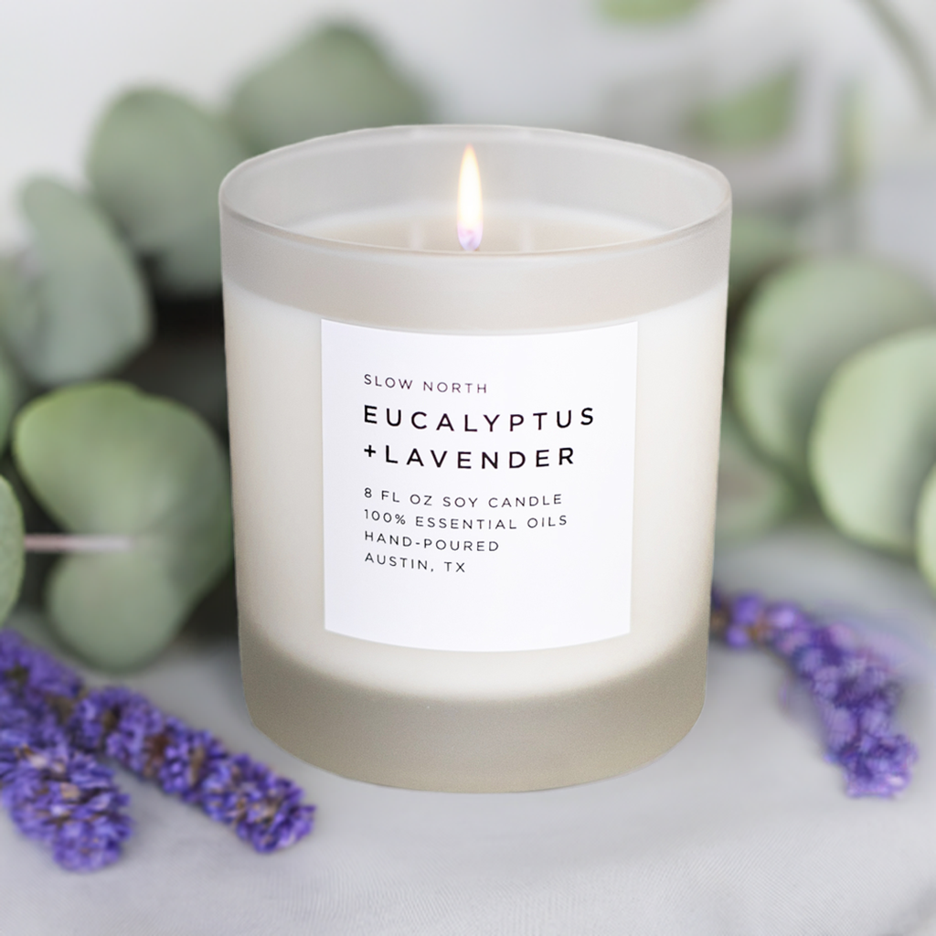 Frosted Slow North Signature Soy Candle with eucalyptus and lavender scent, showing a frosted glass candle holder with botanical accents.