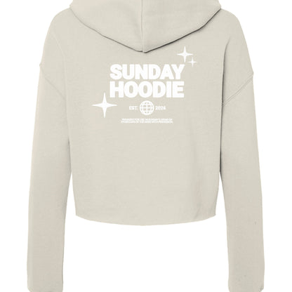 Back view of Omina Essentials beige cropped Sunday hoodie with white graphic print featuring stars and text.