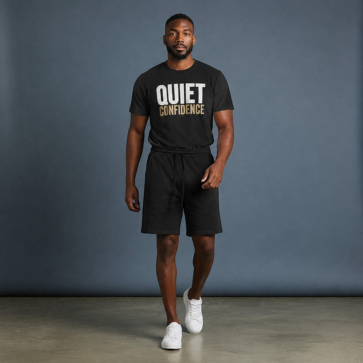 Model wearing Omina Quiet Confidence black cotton t-shirt and matching relaxed-fit shorts with white sneakers