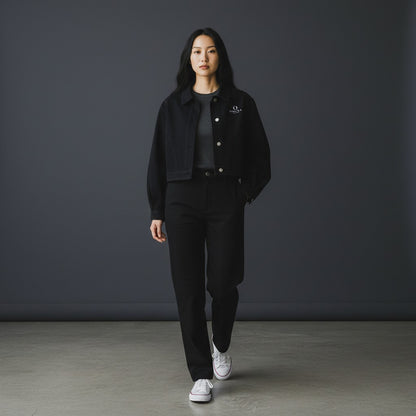 Omina women's black cropped denim jacket with button-front closure, worn by a model with matching black trousers.