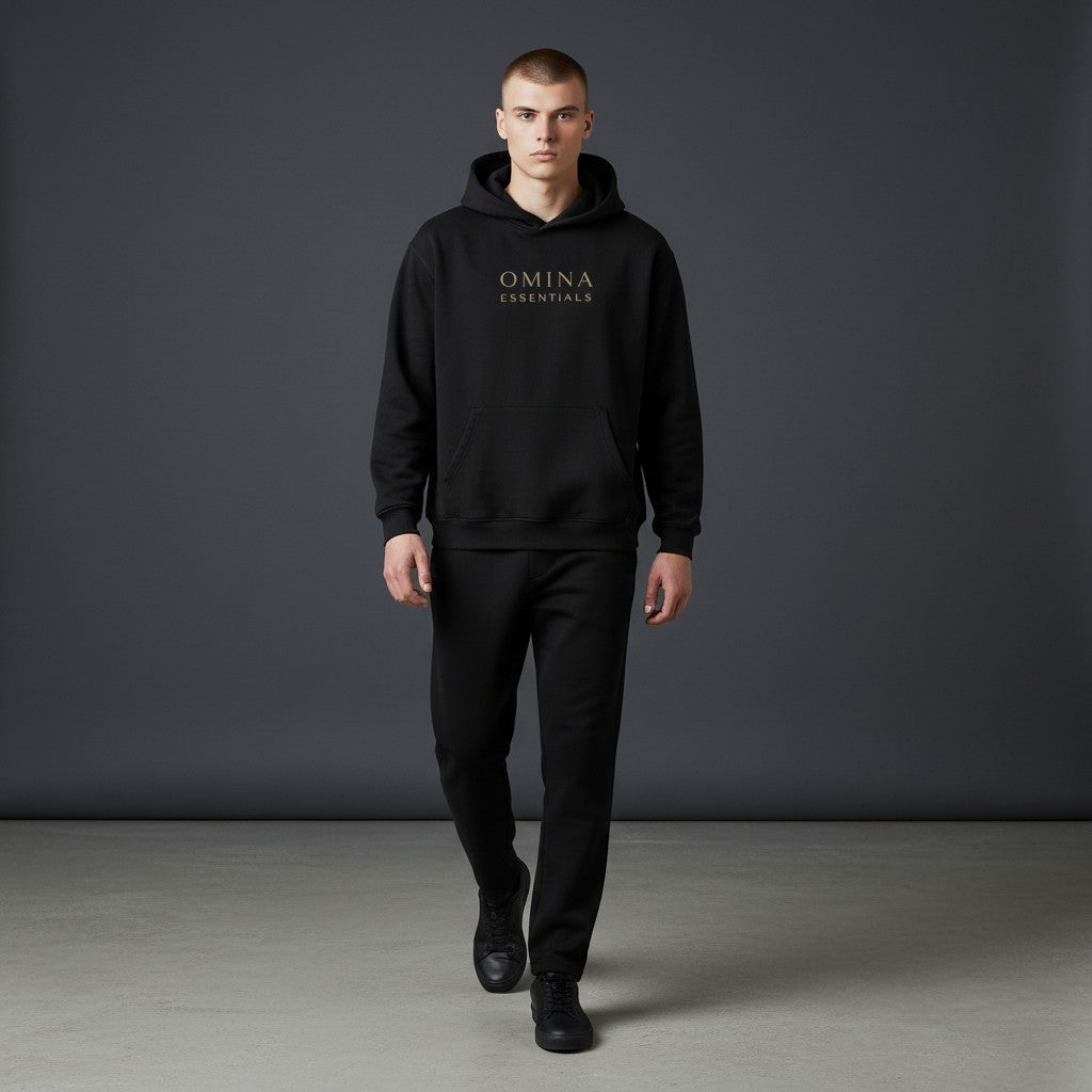 Omina black fleeced boxy hoodie with drop shoulders and ribbed cuffs/hem. Features subtle gold Omina Essentials logo on chest.