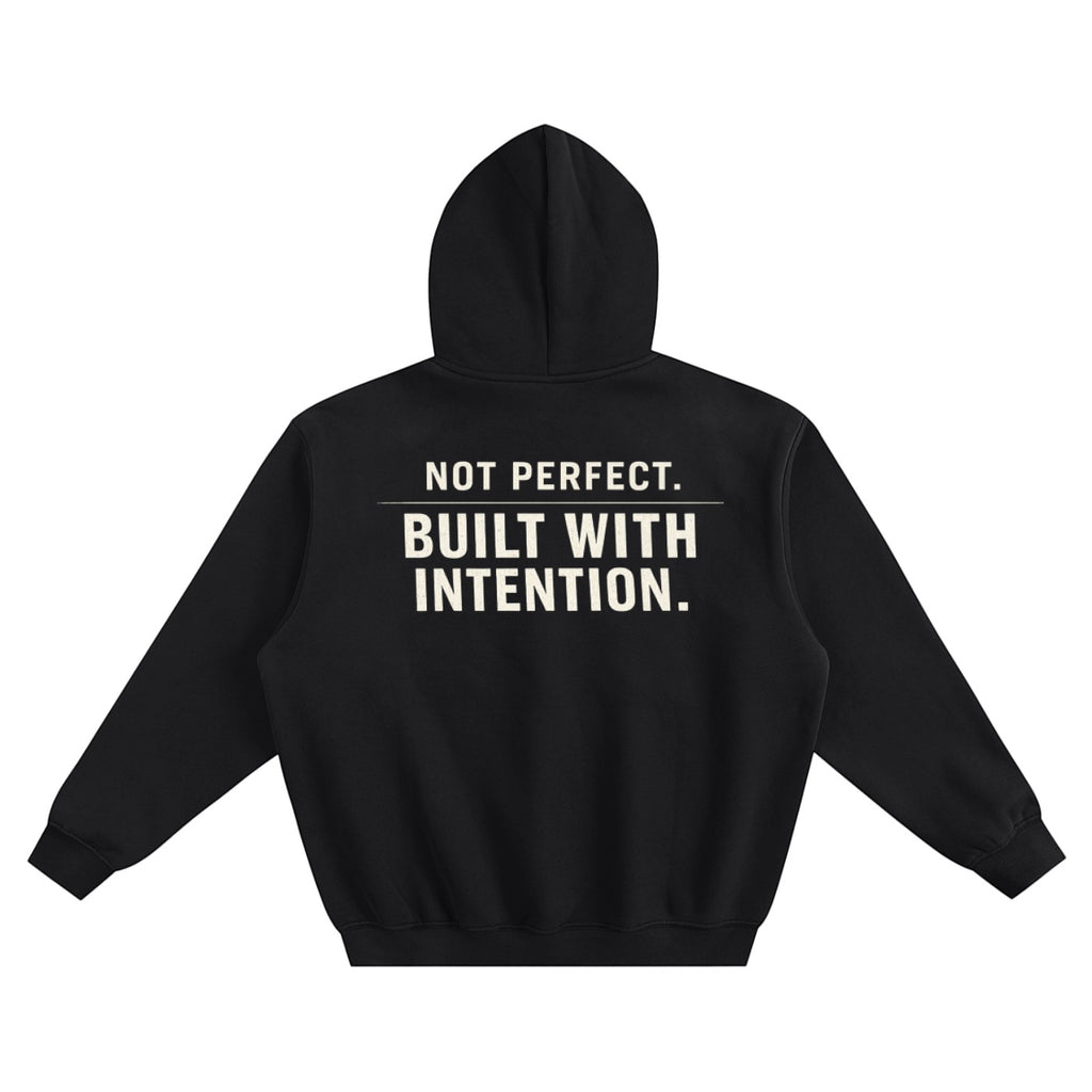 Omina black fleeced boxy hoodie with "NOT PERFECT. BUILT WITH INTENTION." graphic on back.