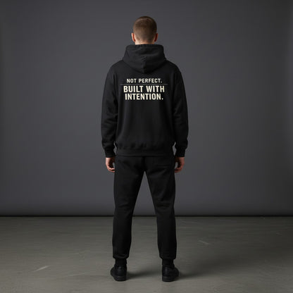 Omina black fleeced boxy hoodie with "NOT PERFECT. BUILT WITH INTENTION." graphic on back.