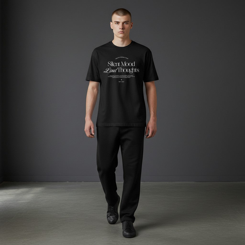 Omina black unisex jersey tee with Silent Mood graphic print worn by a man in a minimalist studio setting.