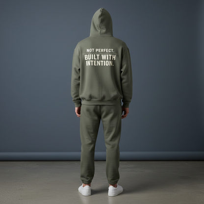 Omina olive green fleeced boxy hoodie with "NOT PERFECT. BUILT WITH INTENTION." graphic on back.