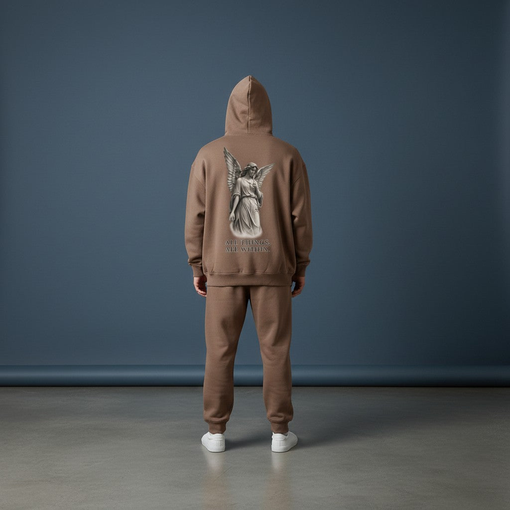 Omina oversized brown fleeced hoodie with angel graphic on back, worn by a model in a studio setting.