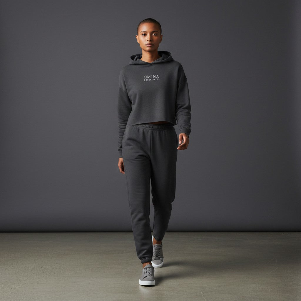 Model wearing Omina Essentials charcoal grey cropped hoodie and matching joggers in a studio setting.