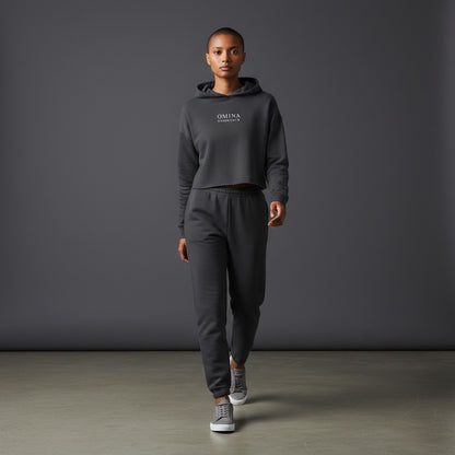 Model wearing Omina Essentials charcoal grey cropped hoodie and matching joggers in a studio setting.