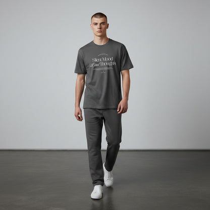 A model wearing an Omina charcoal grey cotton jersey t-shirt with Silent Mood graphic text, paired with matching pants.