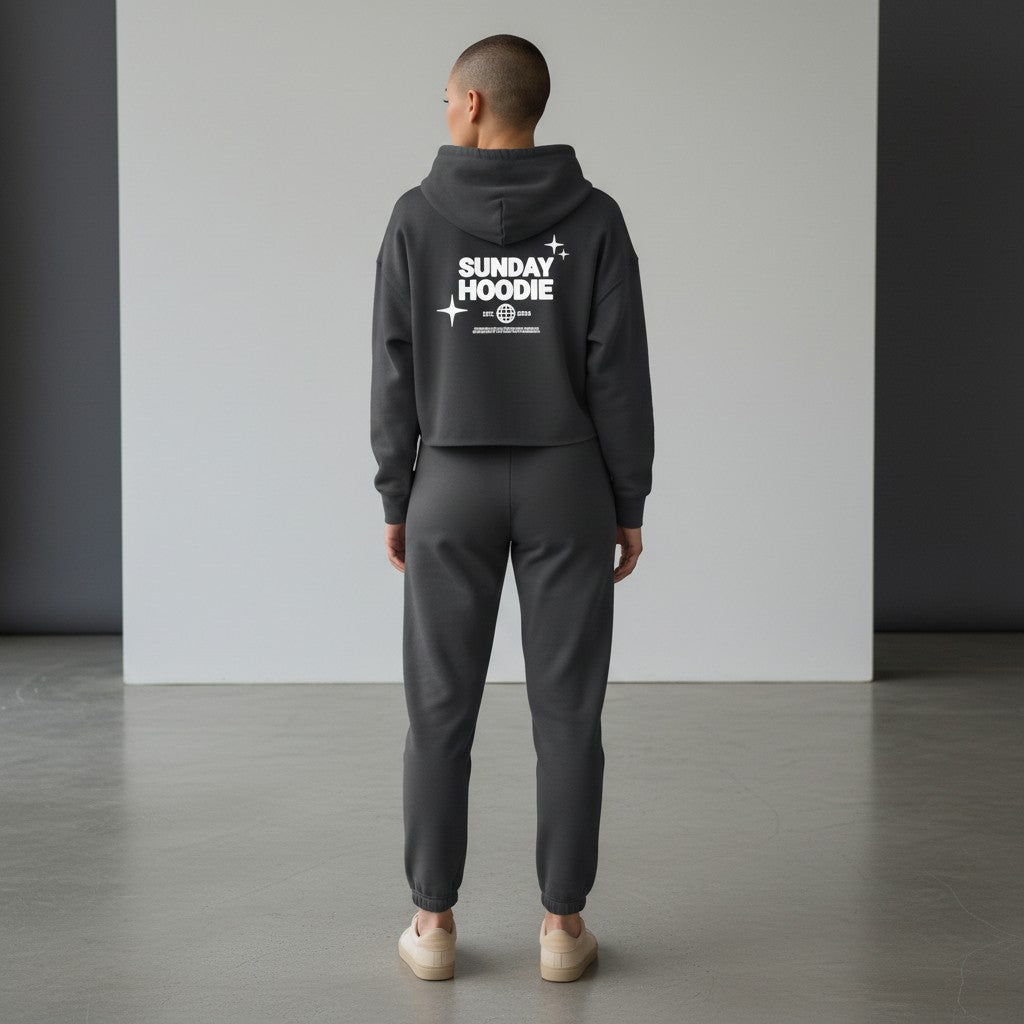 Omina charcoal grey cropped Sunday hoodie with back graphic, worn by a model with matching joggers in a studio.