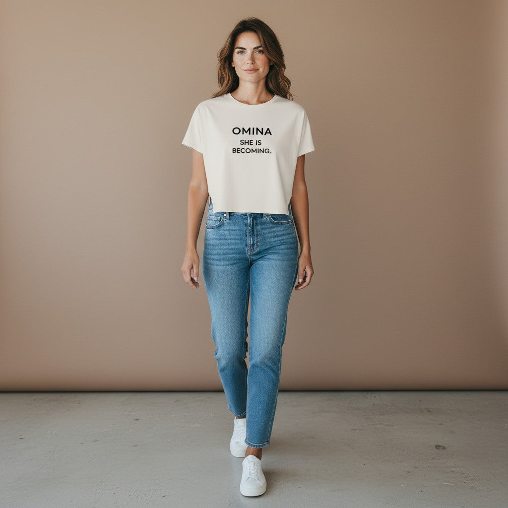 Omina Women's cropped dolman t-shirt in light beige with black text "OMINA SHE IS BECOMING."
