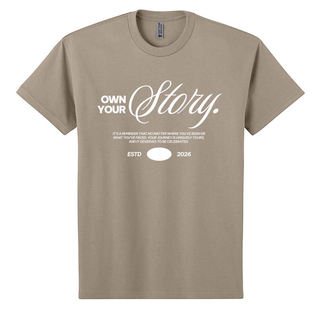 Omina Essentials tan heavyweight cotton t-shirt with white "Own Your Story" graphic and ESTD 2026 detail.