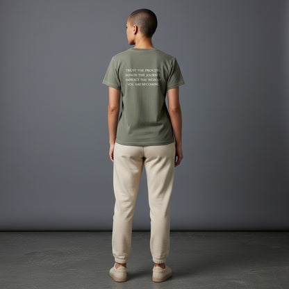 OMINA Essentials olive green cotton t-shirt with vintage wash and white text reading "TRUST THE PROCESS. HONOR THE JOURNEY. EMBRACE THE WOMAN YOU ARE BECOMING."