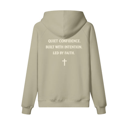 Omina Studio beige heavyweight cotton pullover hoodie with "Quiet Confidence. Built With Intention. Led By Faith." text and a cross graphic.