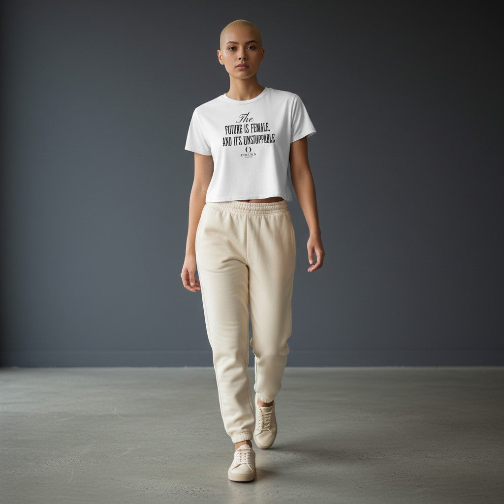 Model wearing Omina white cropped tee with Future is Female graphic, paired with beige sweatpants and sneakers.