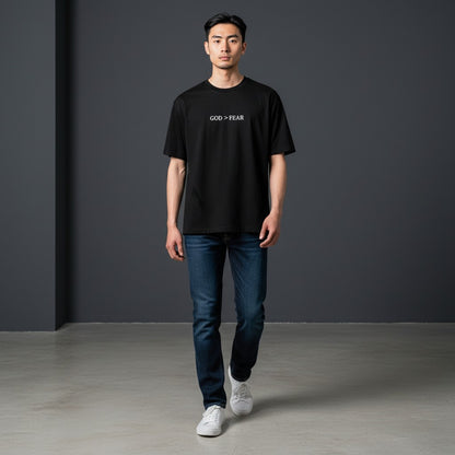 Model wearing a black Omina heavyweight cotton t-shirt with God > Fear text print, styled with blue jeans.
