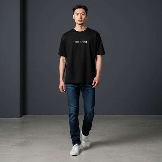 Model wearing a black Omina heavyweight cotton t-shirt with God > Fear text print, styled with blue jeans.