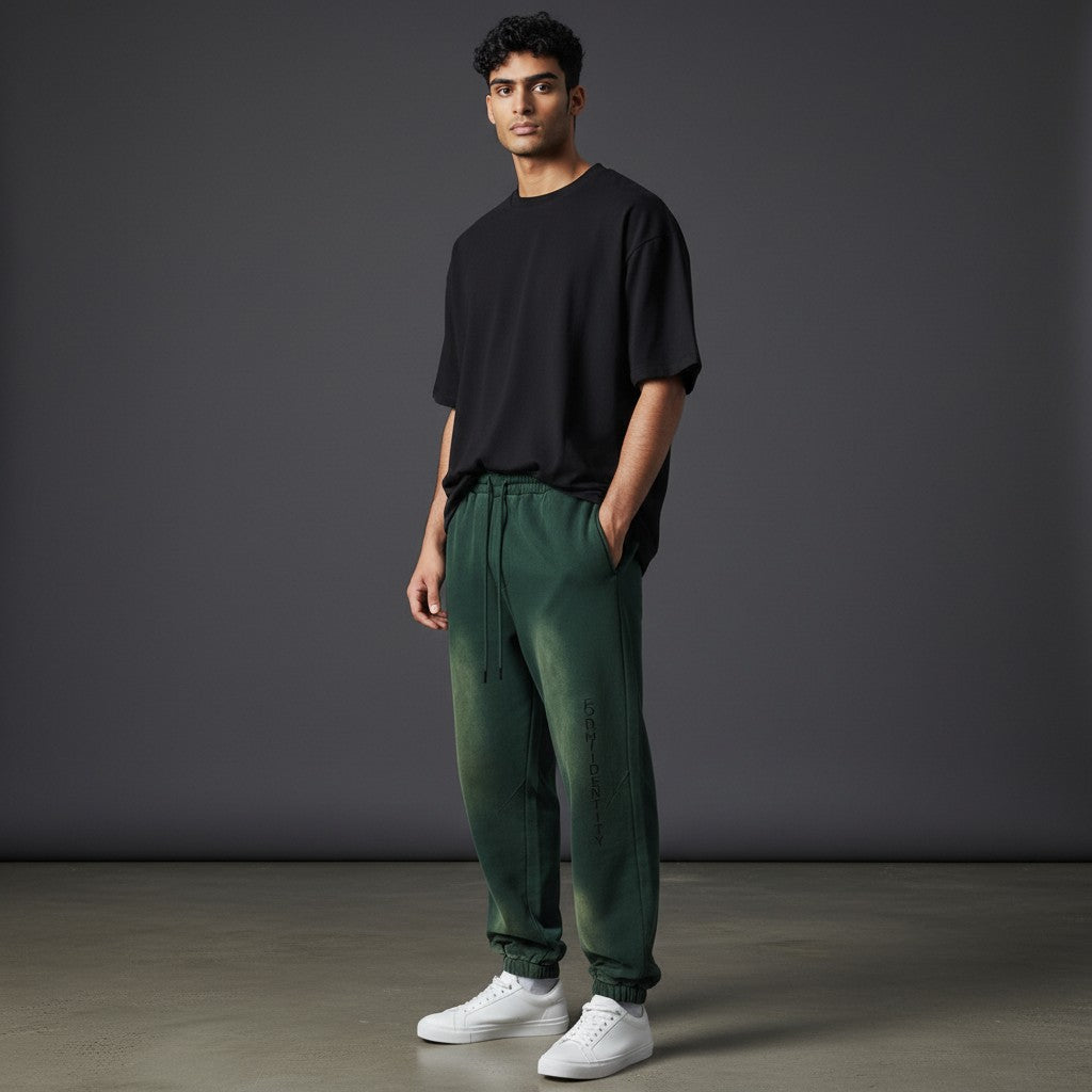 Omina Studio dark green relaxed fit sweatpants with vertical FORM/IDENTITY branding on the left leg.