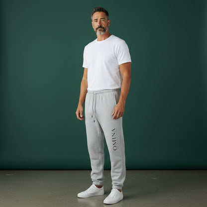 Omina Studio light grey heavyweight cotton blend sweatpants with elastic waistband, drawcord, side pockets, and subtle vertical logo.