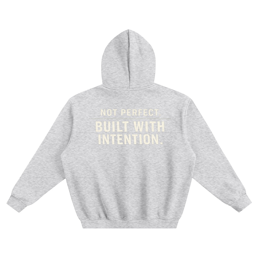 Omina grey fleeced boxy hoodie with "NOT PERFECT. BUILT WITH INTENTION." text on back. Relaxed fit, drop shoulders, ribbed cuffs and hem.
