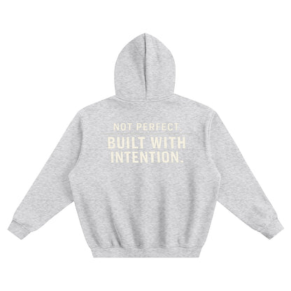 Omina grey fleeced boxy hoodie with "NOT PERFECT. BUILT WITH INTENTION." text on back. Relaxed fit, drop shoulders, ribbed cuffs and hem.