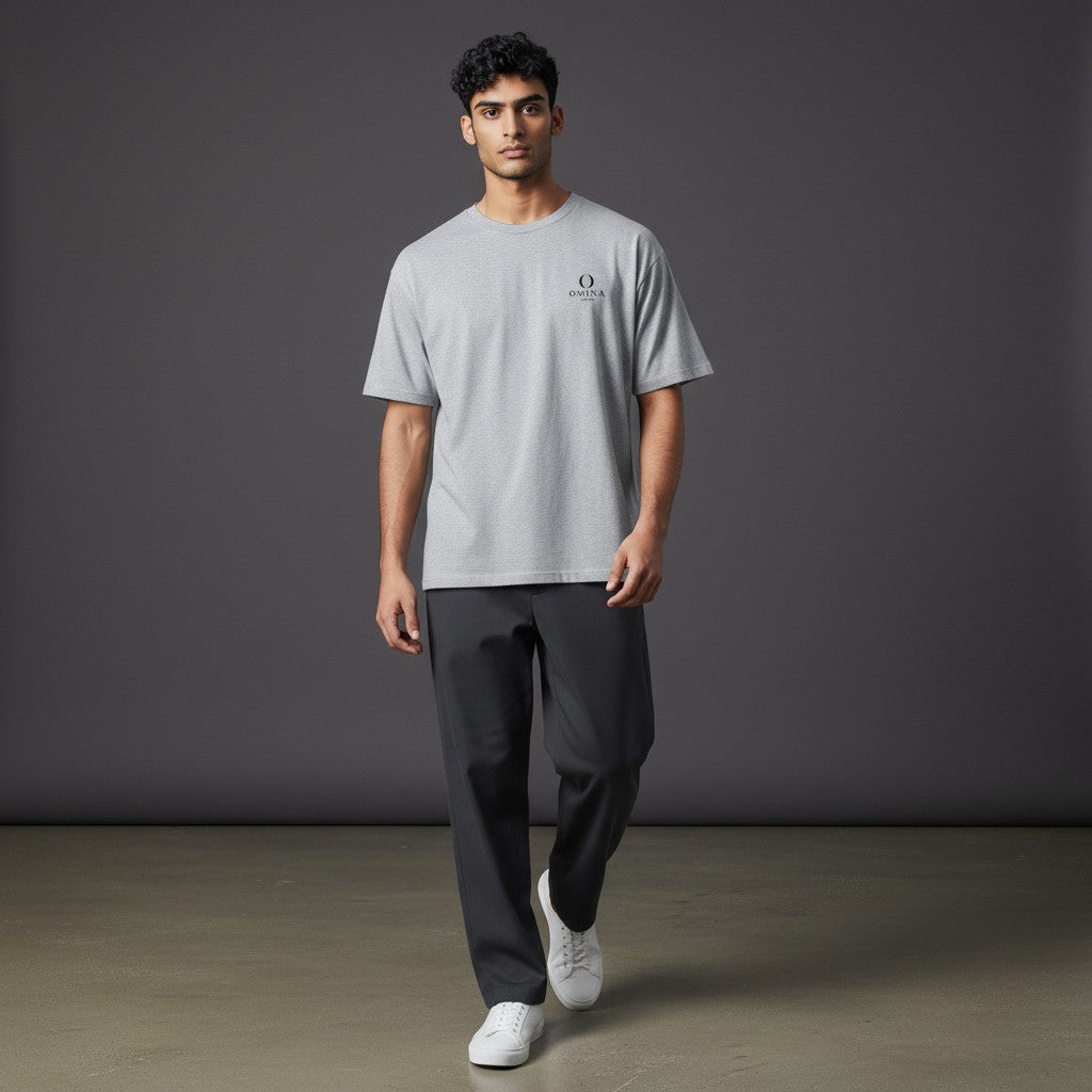 Model wearing a grey Omina heavyweight cotton t-shirt with a small Buddha logo on the chest, relaxed fit.