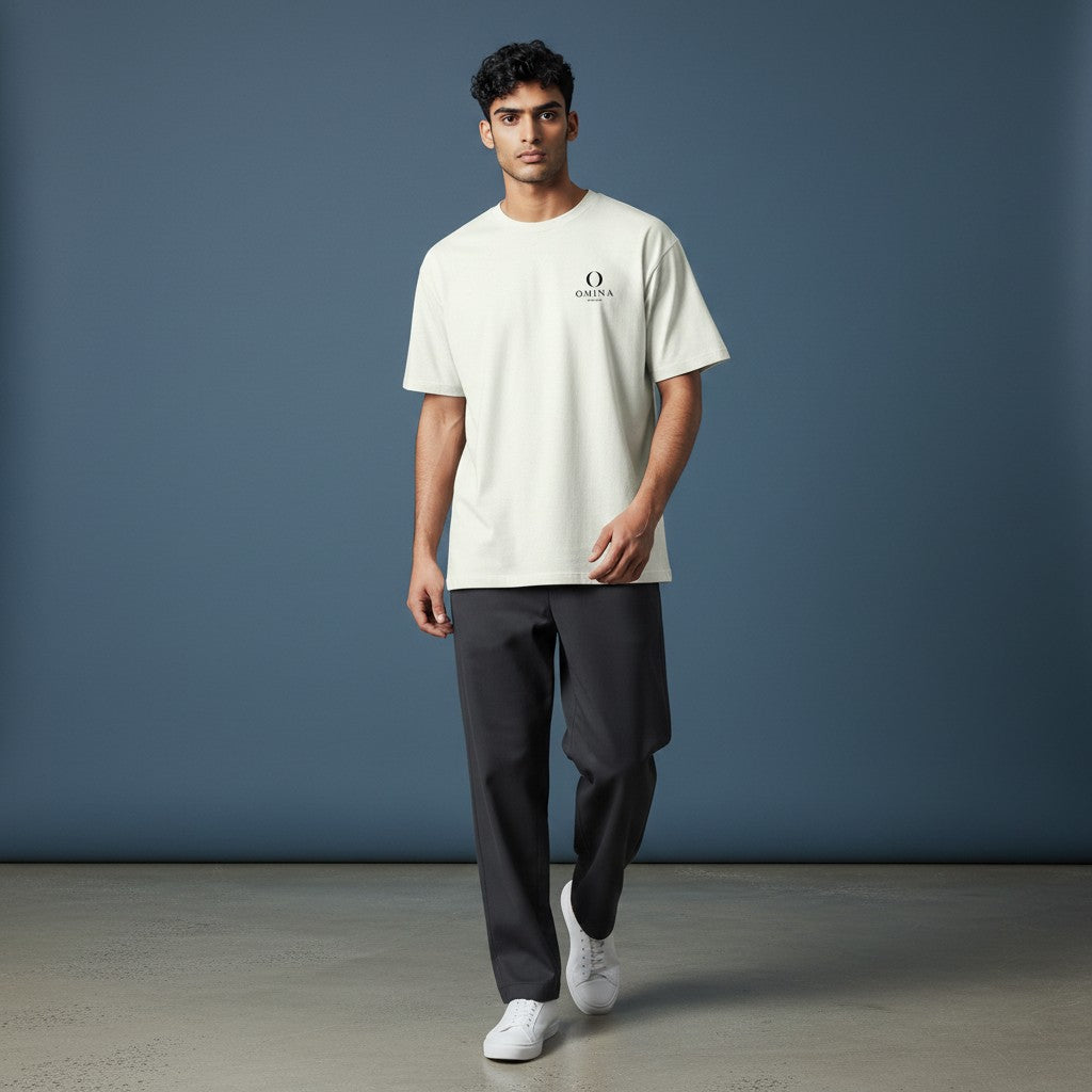 Model wearing an Omina heavyweight cream cotton t-shirt with a small chest logo, styled with dark trousers.