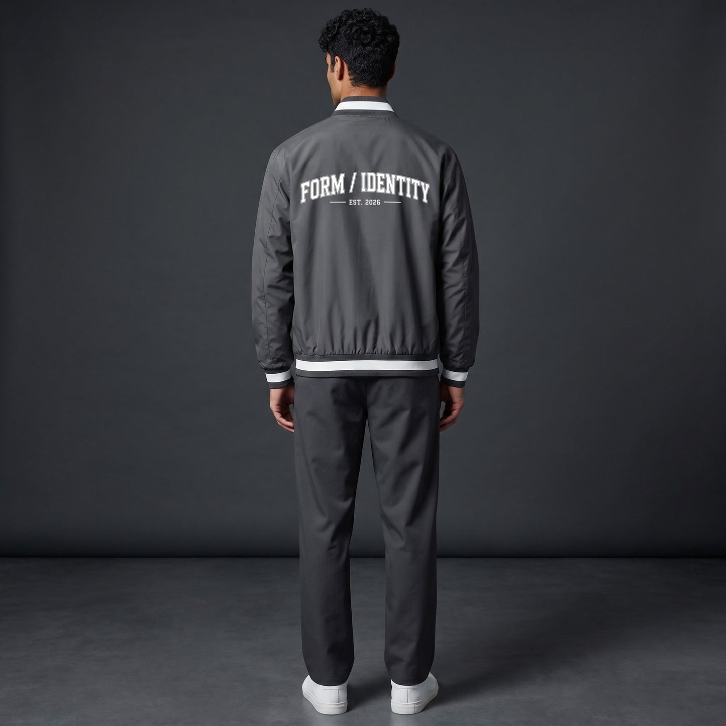 Omina grey insulated varsity jacket with white "FORM / IDENTITY EST. 2026" graphic on back and striped rib-knit collar, cuffs, and hem.