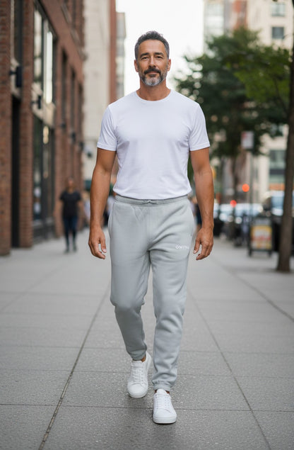 Omina Studio light grey relaxed fit track pants with drawstring waist and cuffed ankles.