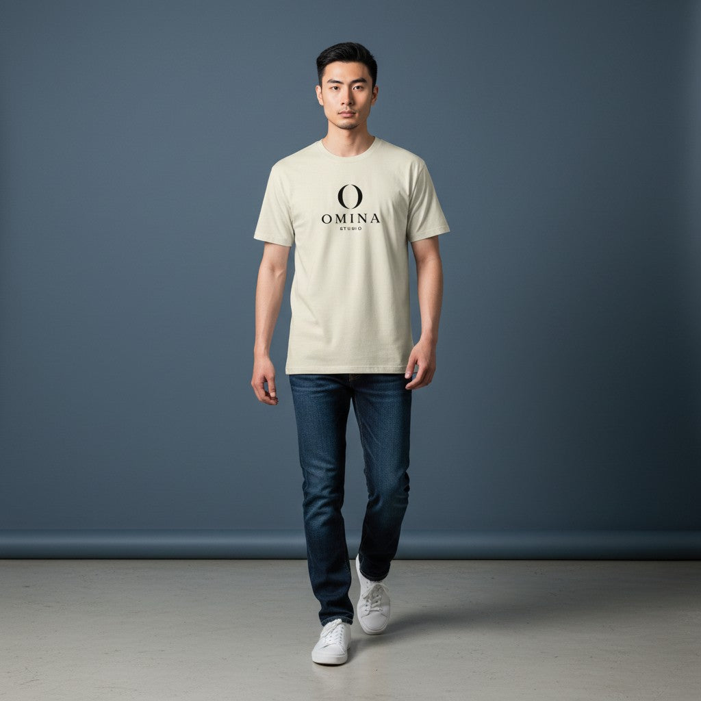 A man wearing an Omina Meet O T-shirt in cream cotton with a black logo graphic, paired with dark blue jeans.