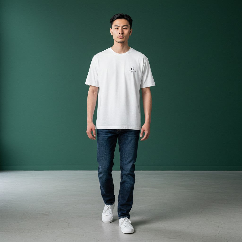 Model wearing an Omina white ring-spun cotton minimalist t-shirt with a small chest logo, paired with blue jeans.