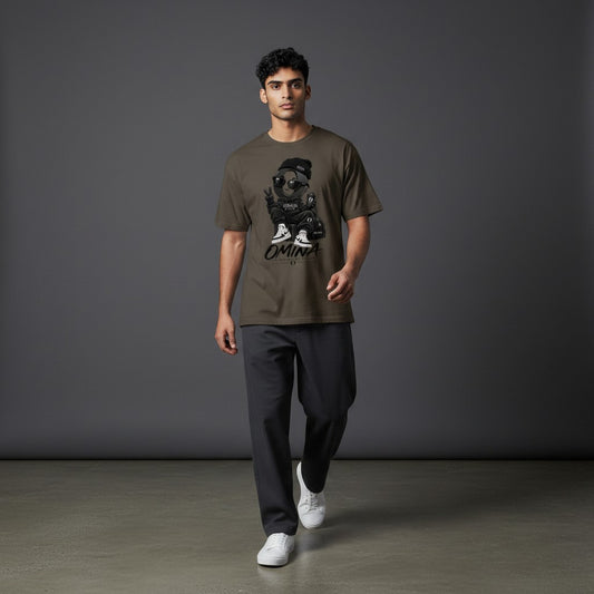 Model wearing an Omina olive green cotton t-shirt with a graphic print of a character in sunglasses and a beanie.