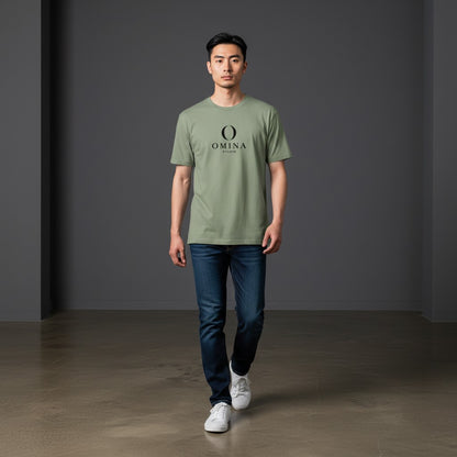 A man wearing an Omina sage green cotton crew neck t-shirt with a black Omina Studio mascot graphic, paired with jeans.