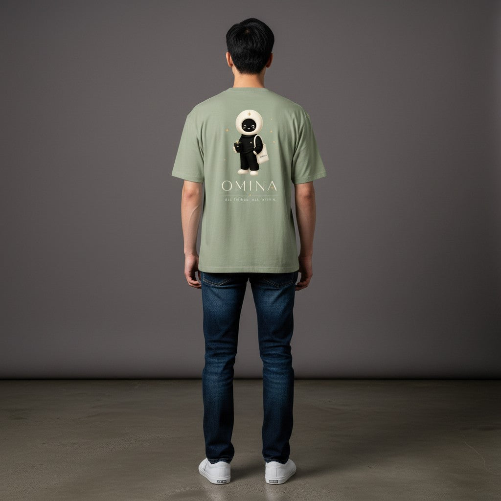 Model wearing an Omina sage green cotton crew neck t-shirt with a back graphic of the O mascot and brand text.