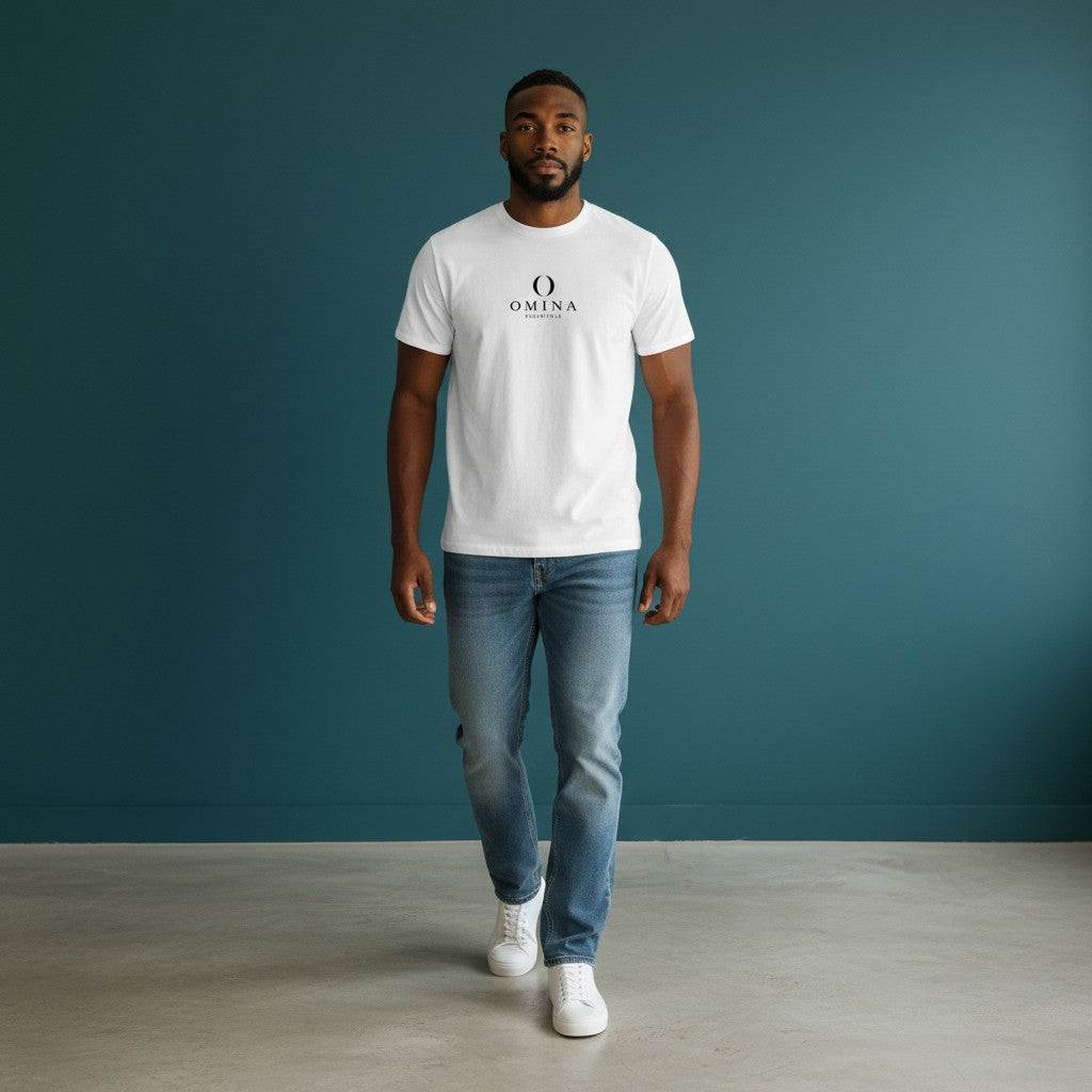 Model wearing a white Omina Essentials seamless cotton crew neck t-shirt with blue jeans against a teal wall.