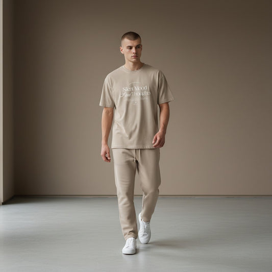Omina Silent Mood unisex jersey tee in beige cotton worn by a man with matching joggers and white sneakers.