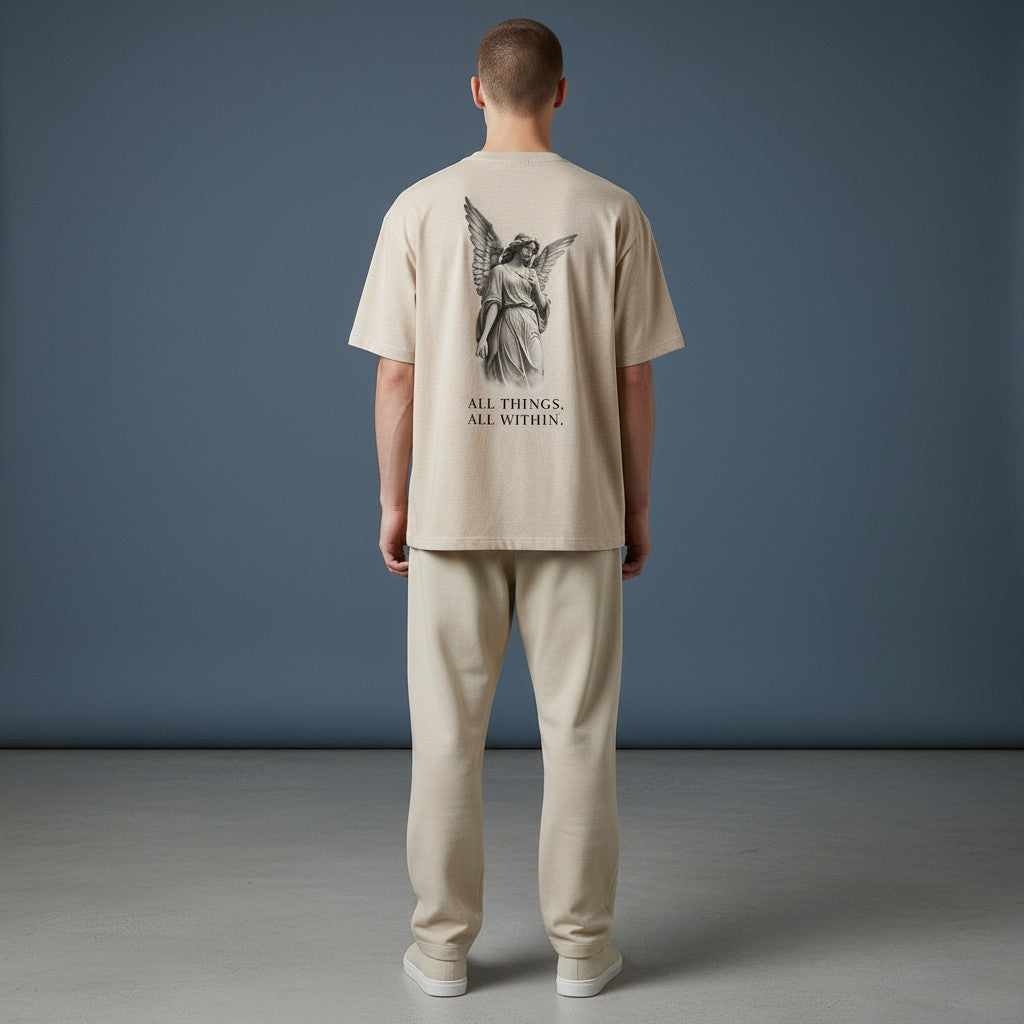 OMINA Studio beige cotton t-shirt with angel graphic and text "ALL THINGS, ALL WITHIN."