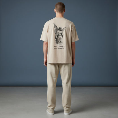 OMINA Studio beige cotton t-shirt with angel graphic and text "ALL THINGS, ALL WITHIN."
