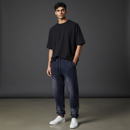 Omina Studio dark wash denim sweatpants with vertical FORM/IDENTITY branding on the left leg and elasticated cuffs.