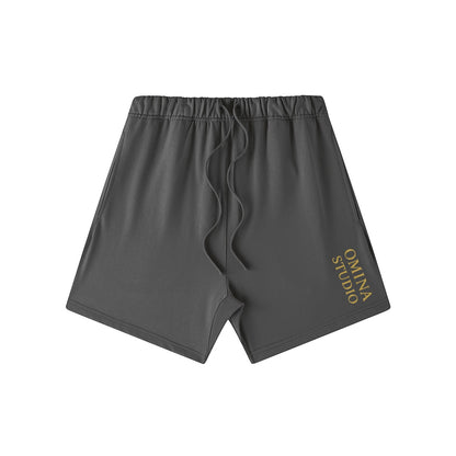 Omina Studio charcoal grey heavyweight French terry cotton shorts with drawstring and gold logo.