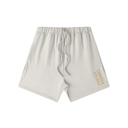 Omina Studio light grey heavyweight cotton French terry shorts with drawstring and gold logo.