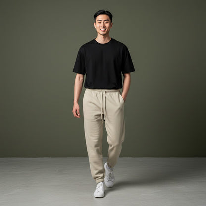 Omina Studio beige 100% combed cotton sweatpants with tapered fit, elastic waistband, drawstring, and cuffed ankles.